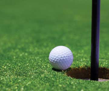 A golf ball on the edge of the hole.