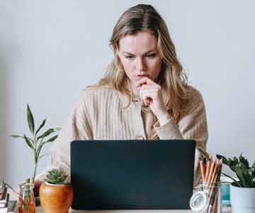 Woman sitting behind a laptop, focused and working.