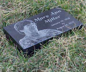 Granite headstone with a picture of a woman named Mary Ann Miller in grass.