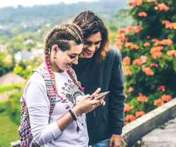 Two couples happily scrolling through a phone together.