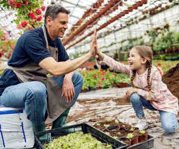 Father and daughter enjoying their time together in a greenhouse.