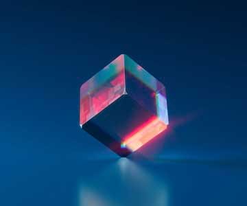 A glass cube spinning around with a dark blue background.