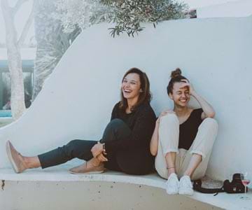 Two women sitting together outside, laughing.