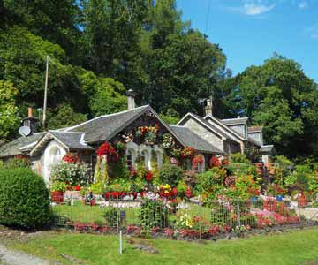 A house with a large and colorful flower garden in front of it.
