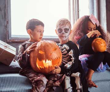 Three Festive Children Dressed In Costume For Halloween With Pumpkins.