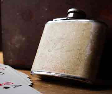Old ivory-colored flasks leaning on a wall beside a playing card. 