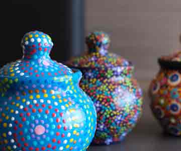 Three floral ceramic vases in blue, red, and green. 
