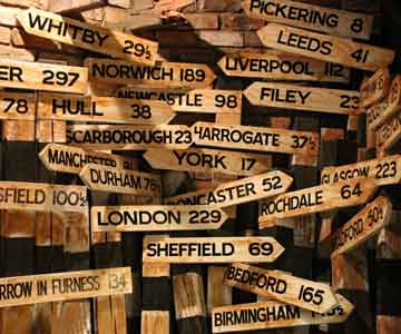 Wooden signs with different locations engraved on the front, pointing in different directions.