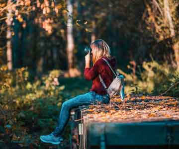 Woman sitting by the creek, taking photos.