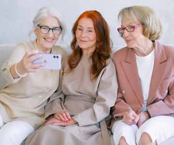 Three elderly ladies joyfully taking selfies together.