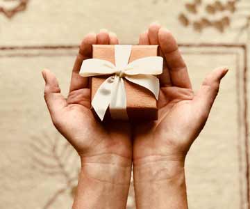 A small pink present in the palms of two hands