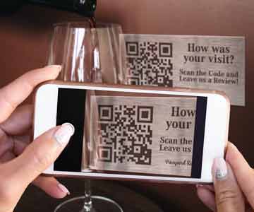 A person scanning a QR code on a stainless steel tag with their smart phone.