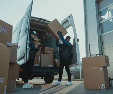 Smiling man carrying a package out of a delivery truck.