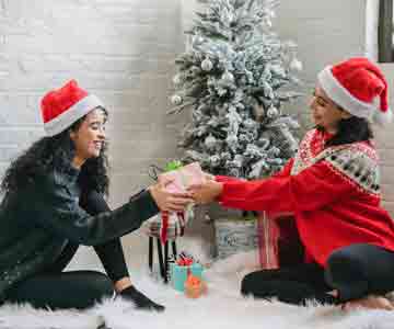 Two joyful women exchanging Christmas gifts.