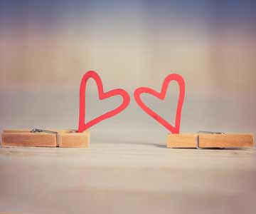 Two paper hearts close together, both being held by clothes pins