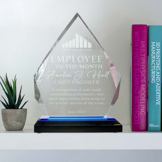 Custom Diamond Shaped Acrylic Award For Employee Of The Month With Blue Mirror Base On White Shelf With Books And Plant