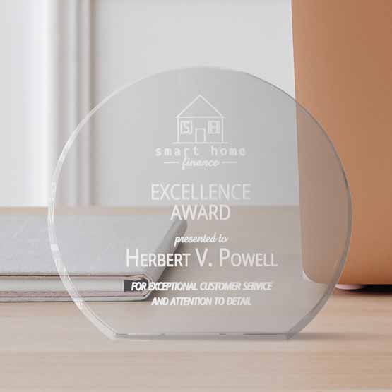 Custom Freestanding Circle Shaped Glass Award For Excellence On A Wood Desk With Notebook And Plant Pot