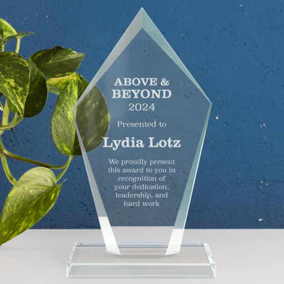 Custom Diamond Shaped Glass Award For Hard Work With Name And Date And Glass Base On A White Shelf With Potted Plant