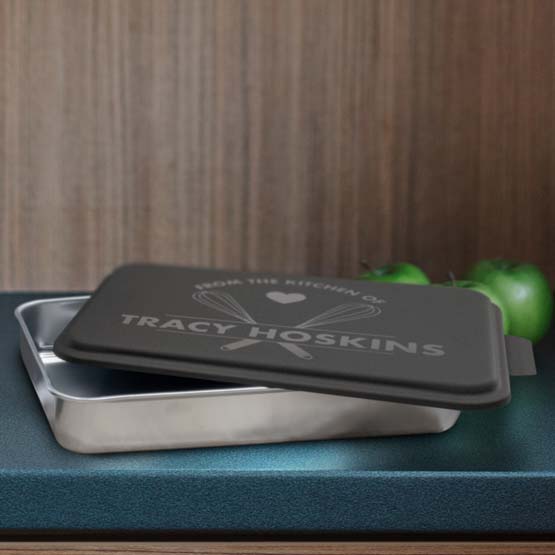 Custom Aluminum Cake Pan With Black Lid Featuring Whisk Artwork And Name On Blue Kitchen Counter With Green Apples