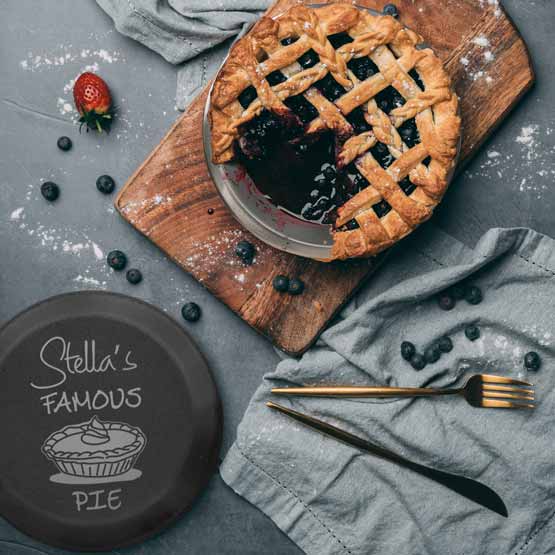 Custom Nine Inch Aluminum Pie Pan With Black Lid Featuring Pie Artwork And Stella’s Famous Pie Text On Table With Pie