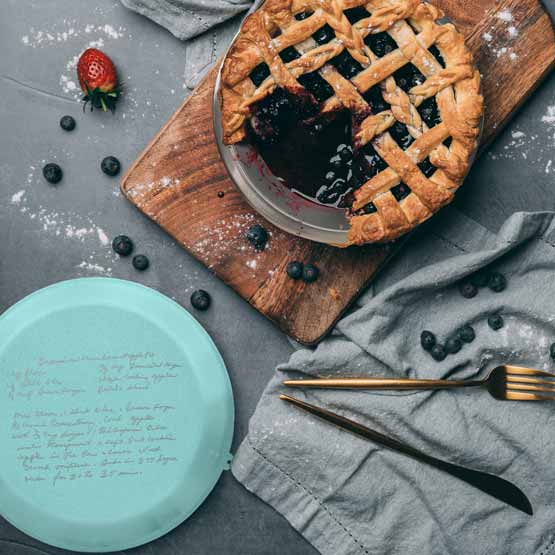 Custom Nine Inch Aluminum Pie Pan With Teal Lid Featuring Laser Engraved Recipe On Table With Berry Pie And Utensils