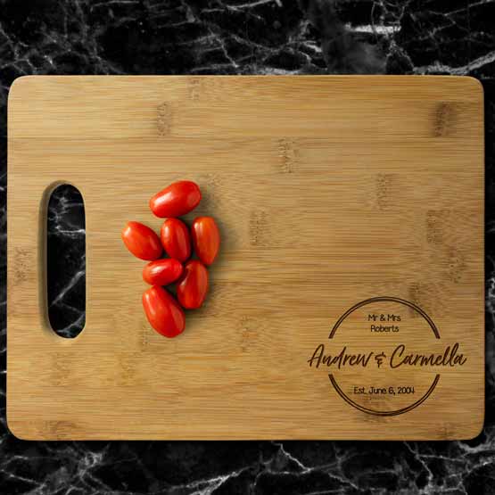 Custom Bamboo Cutting Board With Couple Names And Family Name And Grape Tomatoes Sitting On Marble Kitchen Counter
