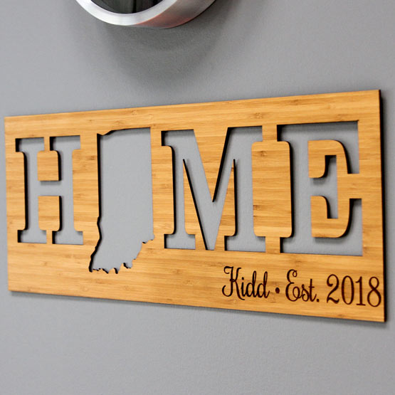 Custom Bamboo Sign With Unique State Shape Inside Cutout Of Home Text And Engraved With Name And Date On Gray Table