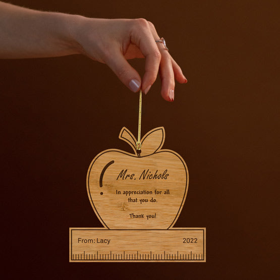 Woman Hand Holding Custom Apple And Ruler Bamboo Ornament Engraved With Teacher Appreciation Message Via Gold String