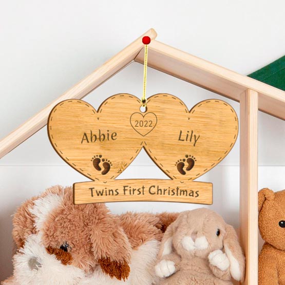 Custom Pair Of Hearts Bamboo Ornament Engraved With Twins First Christmas And Names Hanging Via Baby Crib Near Dolls
