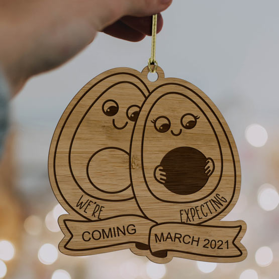 Hand Holding Custom Bamboo Ornament Laser Engraved With Avocado Parents And Baby Art And We’re Expecting Message And Date