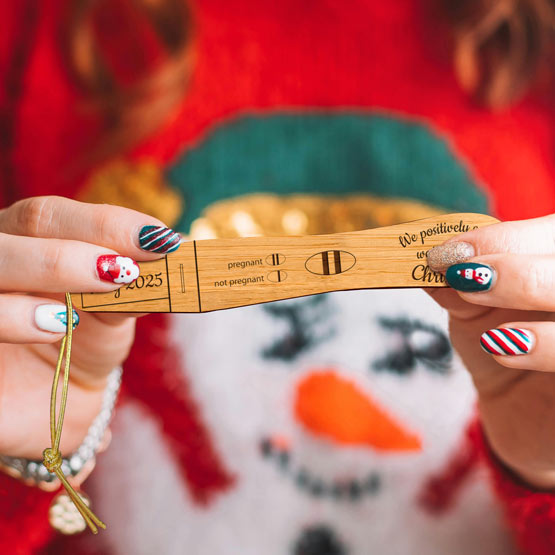 Festive Woman Holding Custom Pregnancy Test Shaped Bamboo Ornament Laser Engraved With Date And Can’t Wait For Christmas Text
