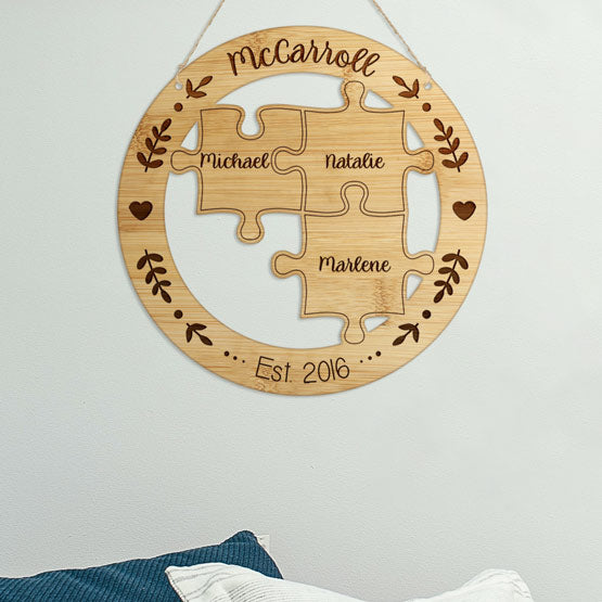 Custom Bamboo Sign With Puzzle Pieces Cutout Inside A Circle And Engraved With Family Names Hanging On Living Room Wall