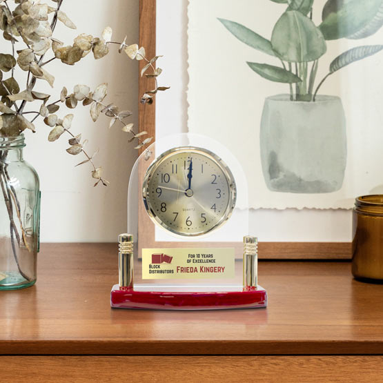 Custom Arch Shaped Glass Desk Clock With Rosewood Base And Metal Plate With Years Of Service Award Text On Dresser With Plant