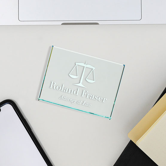 Custom Glass Paperweight Engraved With Justice Scale Artwork And Roland Fraser Attorney At Law On Work Desk With Laptop