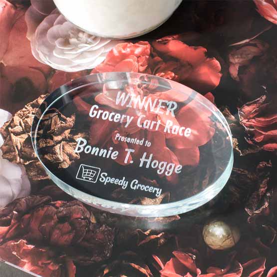 Custom Oval Glass Paperweight Award For Grocery Cart Race With Name And Speedy Grocery Logo On A Table With Rose Art