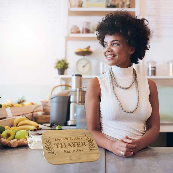 Happy Woman At Kitchen Counter With Food And Rectangle Glass Baking Dish Featuring Bamboo Lid Engraved With Names And Date