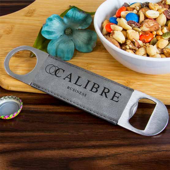 Stainless Steel And Gray Faux Leather Bottle Opener Engraved With Business Logo On Paddle Cutting Board With Bowl Of Nuts