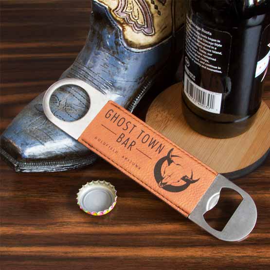 Stainless Steel And Rawhide Faux Leather Bottle Opener Engraved With Ghost Town Bar Logo Leaning On Shoe And Beer Bottle