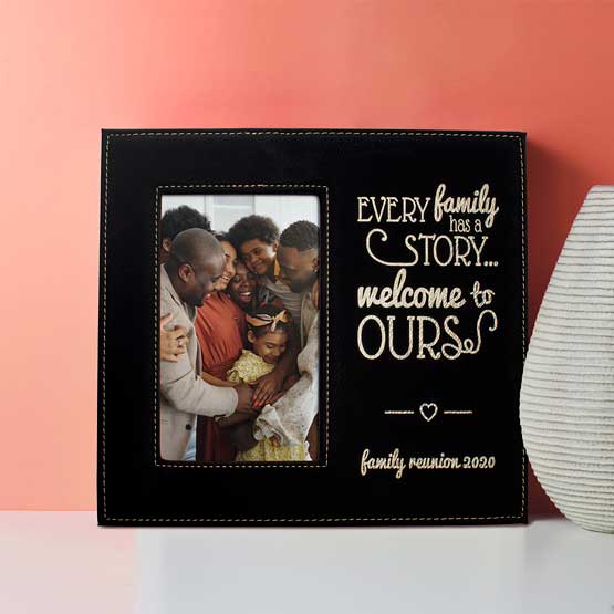 Black And Gold Faux Leather Picture Frame With Family Photo And Engraved With Family Story Message On Shelf With Vase