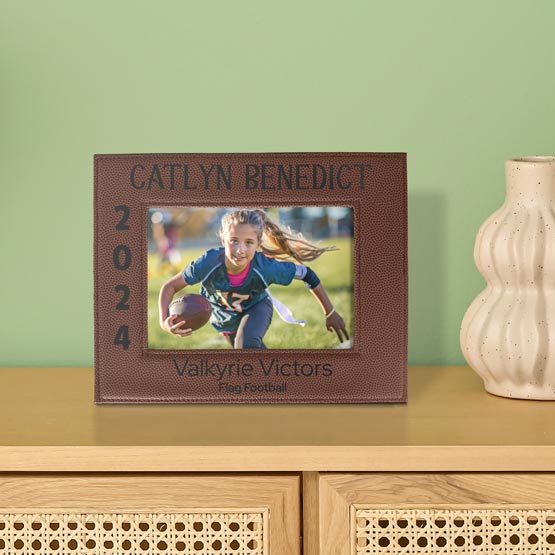 Faux Leather Picture Frame With Brown Football Theme And Player Photo And Team Details Engraving On A Dresser With Vase