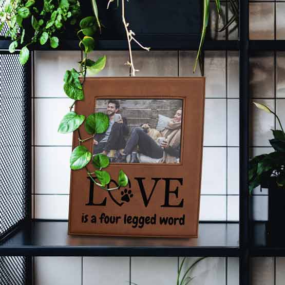 Rawhide Faux Leather Picture Frame With Photo Of Couple And Dog And Engraved With Love Message On Bookshelf With Plants