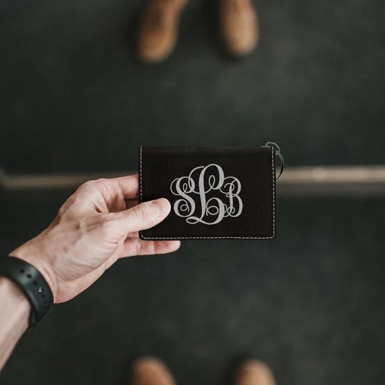 Man Hand Holding Custom Black And Silver Faux Leather Keychain Wallet ID Holder Laser Engraved With Ornate Initials
