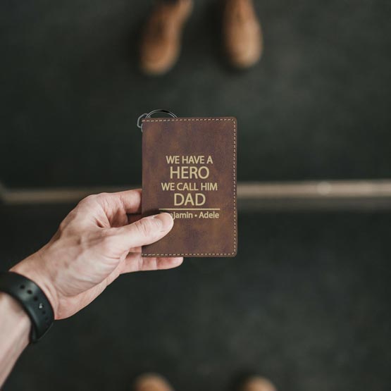 Man Hand Holding Rustic Faux Leather Keychain Wallet ID Holder Engraved With Names And We Have A Hero We Call Him Dad