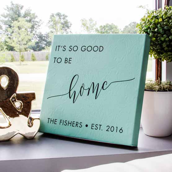Teal Faux Leather Wrapped Square Canvas Engraved With Family Name And Date And It’s So Good To Be Home On Bright Window Sill