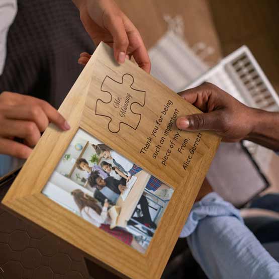 Hands Gifting Red Alder Picture Frame With Teacher Photo And Engraved With Puzzle Piece Art And Names And Thank You Message