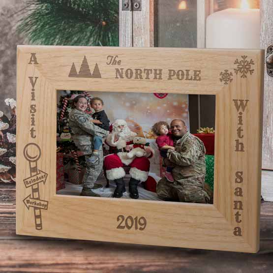 Red Alder Picture Frame With Photo Of Santa With Family And Engraved With North Pole Santa Visit Text And Date On Wood Shelf