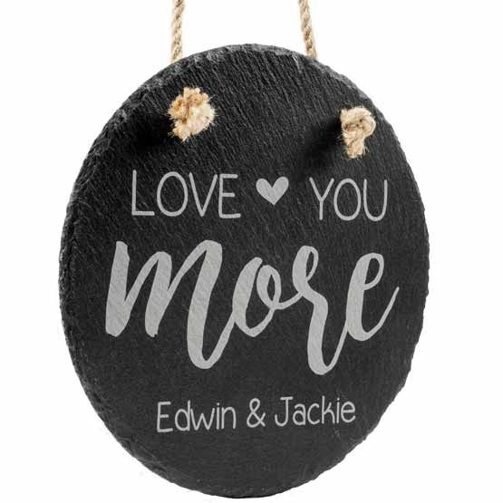 Custom Circle Slate Sign With Printing Of Love You More And Couple Names Hanging Via Rope Against White Background