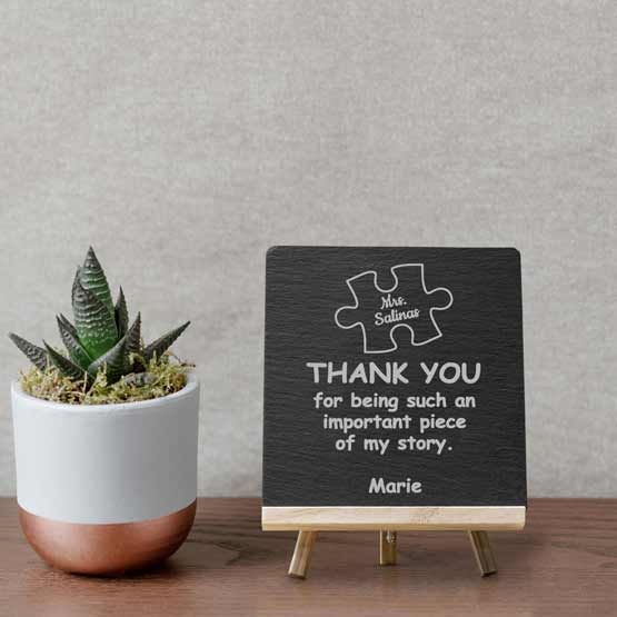 Slate Sign Printed With Teacher Appreciation Message And Puzzle Piece Art Standing On Shelf With Plant Via Wooden Easel