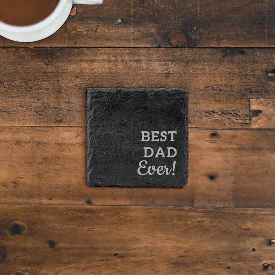 Custom Slate Square Coaster Printed With Best Dad Ever Message Displayed On A Wood Table Nearby Filled Coffee Mug