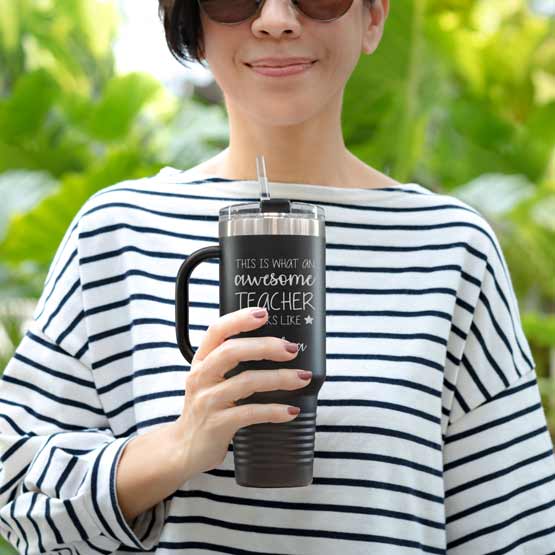 Happy Woman Outdoors Holding Black Stainless Steel Coffee Tumbler With Handle And Straw And Engraved With Teacher Message